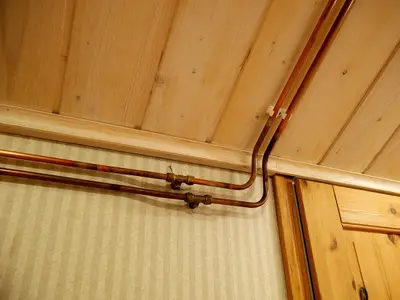 Copper water pipes running along a wall and ceiling