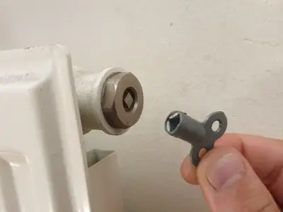 A radiator key next to a radiator bleed valve